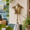 Brass sea turtle wall hook mounted on a teal tiled wall holding a towel, nautical coat hook from the ocean animal set.