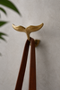 Brass whale tail wall hook holding rope, coastal nautical wall hook for entryway or bathroom decor