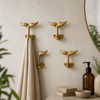 Solid brass whale tail wall hook set of 4 styled in a coastal bathroom, used as towel hooks and entryway wall hooks. Nautical decor for beach house interiors, minimal brass wall hooks for towels, bags, and keys.