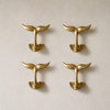 Pair of brass whale tail wall hooks on a neutral wall. Coastal nautical wall hooks for towels, keys, or bathroom decor in minimal beach house interiors