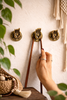 Buddha hand mudra hooks mounted on wall, small brass hooks for keys, jewelry, towels or leash holder in entryway or bedroom.