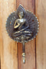 Close-up of brass Buddha wall hook with antique finish on wooden surface showing texture detail