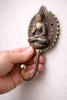Hand holding brass Buddha wall hook showing size and detailed craftsmanship for wall decor
