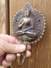 Centered brass Buddha wall hook on wooden wall for zen decor and meditation room styling