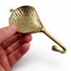 Backside of brass clam shell wall hook showing mounting hardware and curved hook