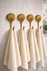 Brass clam shell wall hook set of 4 holding towels in a coastal bathroom
