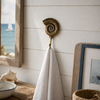 Brass ammonite fossil wall hook styled in beach house bathroom holding towel