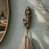 Crowned brass mermaid wall hook mounted on a blue wall holding a towel, coastal nautical decor from the mermaid hook set.