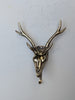 A brass deer skeleton wall decor hook with two holes for mounting.