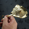 Close-up of a hand holding a handcrafted brass stingray wall hook, showing the solid brass texture from the nautical hook set.