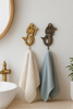 Mermaid-shaped towel hooks with white and blue towels in a coastal bathroom setting.