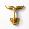 Large brass whale tail wall hook close up, statement coastal decor hook for towel, coat or nautical wall styling