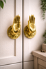 Mini brass hand cabinet pulls mounted on cabinet doors, left and right set in gold finish