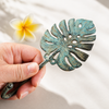 Hand holding monstera leaf wall hook showing real size and scale for wall mounting use