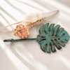 Patina monstera leaf wall hook styled with seashells, coastal tropical home decor inspiration