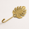 Side angle view of brass monstera leaf wall hook showing curved hook design and structure