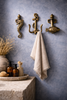 Brass fish seahorse and anchor wall hooks styled in coastal bathroom with hanging towel