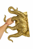 Hand holding single octopus tentacle brass door pull to show oversized scale and detail