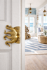 Large octopus tentacle brass door pull installed on a light coastal-style door
