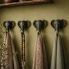 Set of four patina brass elephant wall hooks mounted on deep olive green boho wall with natural linen towels and macrame bead strand hanging showing dramatic eclectic gallery wall lifestyle styling. Handcrafted verdigris patina elephant coat hook set and towel hook set for boho housewarming gift, yoga room decor, meditation space decor and wabi sabi home decor. Unique eclectic gallery wall hook set of 4