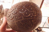 Hand carved coconut shell light cover with perforated pattern for bistro string lights