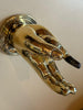 Close-up angled view of polished brass hand hook on wall, sculptural statement hook for entryway or bedroom