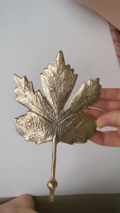 Video showing hand mounting a brass maple leaf wall hook