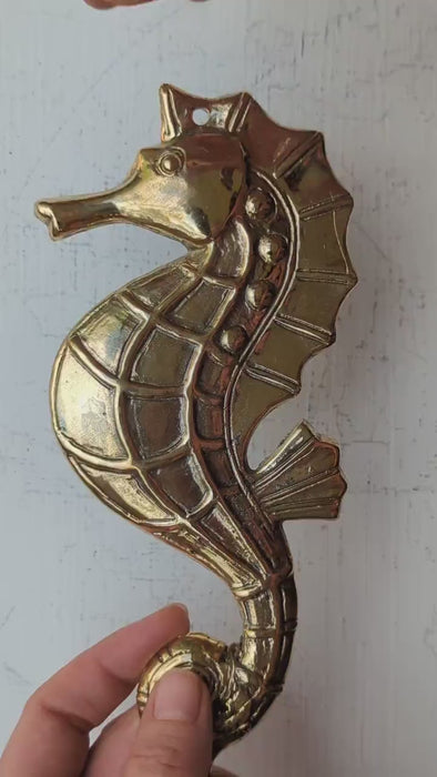 Video of solid brass seahorse wall hook held in hand showing detailed scale texture fin detail and full sculptural body for scale — nautical seahorse hook set of 4 coastal decor handmade in Bali