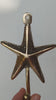 Video close-up of the brass textured starfish wall hook held in a hand, showing the detailed sea star arms, the top screw loop and the ball-tipped hook. Handmade cast brass coastal hook from Ubud, Bali.