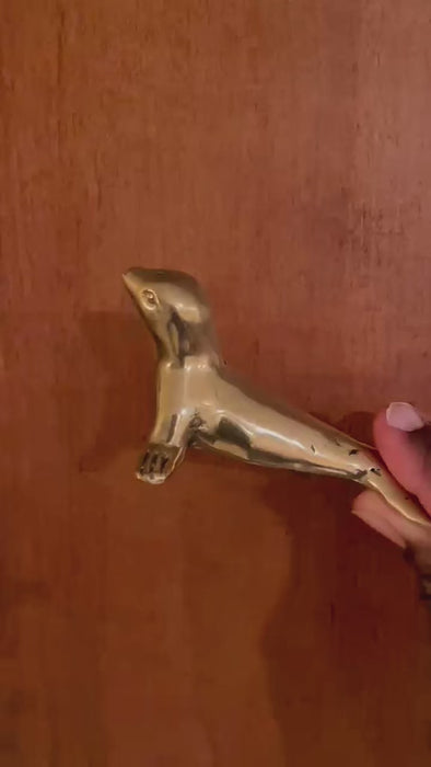 Video of the brass seal bottle opener held in a hand and turned to show the seal's polished gold brass body, flippers and bottle-opening loop. Handmade animal bottle opener from Ubud, Bali.