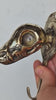 Solid brass dinosaur skull wall hook held in hand showing scale and antique brass finish — gothic dinosaur hook man cave decor handmade in Bali