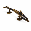 Antique finish brass dolphin door handle shown on white background, vintage coastal door pull.