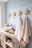 Set of 4 brass sea star wall hooks styled in coastal bathroom with hanging towels