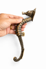 Hand holding seahorse cabinet pull showing size and detail of solid brass nautical drawer handle