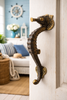 Antique brass seahorse entry door handle installed on door in coastal beach house interior