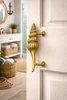 Solid brass seashell door handle installed on coastal bathroom door in beach house interior