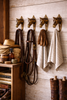 Set of four brass horse wall hooks in tack room holding riding gear and towels, rustic equestrian stable decor