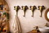 Set of four ram skull wall hooks installed in a bathroom as towel hooks and robe hooks, handmade brass wall decor