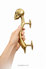 Hand holding skull spine door handle side profile showing mounting posts and scale