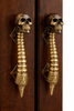 Matching skull spine door handle pair installed on wooden double doors for dark academia entry style