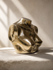 Small gold brass female torso sculpture in dramatic side light on a textured stone surface — maximalist decor sculptural decor piece, man cave decor and after dark statement
