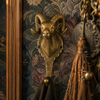 Solid brass ram wall hook in polished gold finish mounted on a dark academia wall with ornate floral tapestry and gold tassel — handmade in Ubud Bali