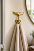 Brass whale tail wall hook holding towel in bathroom, coastal decor hook set detail, nautical home accessory