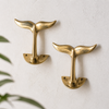 Pair of brass whale tail wall hooks styled on wall, minimal coastal decor hooks for towel hanging or entryway organization