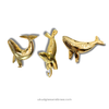 Gold brass whale towel hook mounted in a coastal bathroom setting