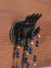 Close-up brass mudra hand hook holding beaded jewelry, wall-mounted