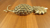 Decorative Gold Brass Pineapple double hook from the side laying on the wooden table 