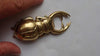Solid brass beetle bottle opener held in hand to show size and grip