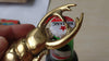 Scarab beetle brass bottle opener lifting a bottle cap during use