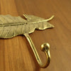 Side close-up of brass feather wall hook on 3-hook rack, sturdy curved hook for towels, bags, and keys